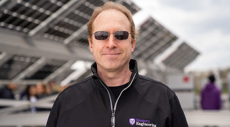 Man with sunglasses with solar panels in background